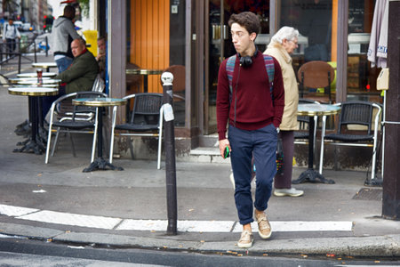 Paris, France - September 23, 2017: guy with cell phone crossing street, street cafe. Street lifeのeditorial素材