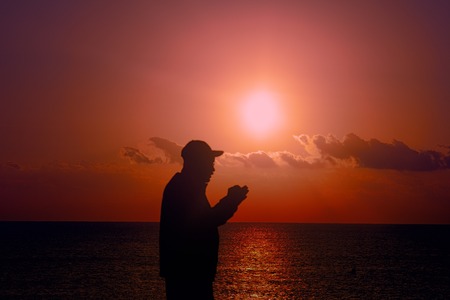 Journey and coordinates in space. Silhouette of tourist on background of setting sun and sea, with...