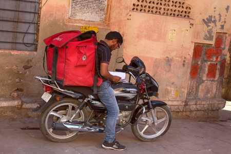 India, Jaisalmer - March 5, 2018: modern courier delivery of orders in India by young Indians on a motorcycleのeditorial素材