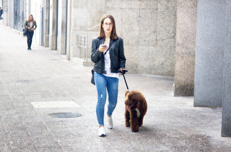 Spain, Girona - October 1, 2017: girl with a poodle on a city streetのeditorial素材