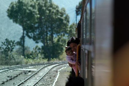 India, Western Himalayas - March 18, 2018: Train from Kalka to Shimla. Young woman with suckling in the doorway, from the train on the goのeditorial素材