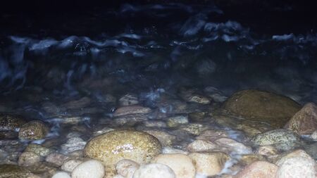 Night sea., night walk. Pebble beach and roll in a narrow spot of lightの写真素材