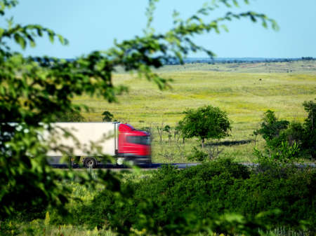 Blurred unrecognizable truck transport on road. Transport overpasses on the highway for the transport of orders and goodsの写真素材