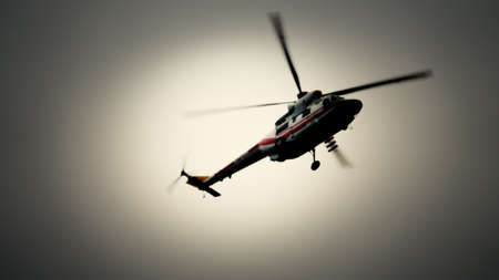 Blurred unrecognizable helicopter in a cloudy sky. Air transport at workの写真素材