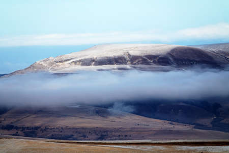 Picturesque foothills of the Caucasus in autumn. A layer of low clouds over the valley and hills, bald mountainの写真素材