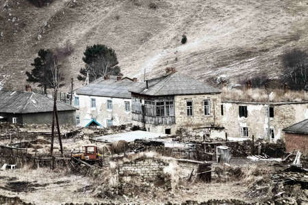 Dying mountain villages (aul) in the Caucasus. Dilapidated houses in winter. Houses and farms are fenced. Poor farmsの写真素材