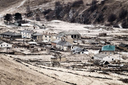 Dying mountain villages (aul) in the Caucasus. Dilapidated houses in winter. Houses and farms are fenced with a fence of unfixed stonesの写真素材