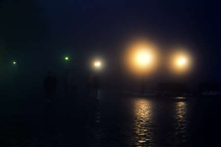 Winter foggy night city (thick weather). Late passers-by, strollers, cars, fog lightsの写真素材
