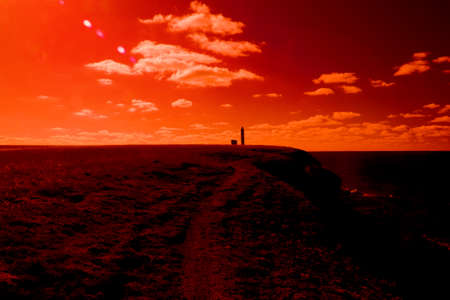 An ancient lighthouse on edge of a cliff. The magic and beauty of the sea. Surrealistic art infrared photoの写真素材