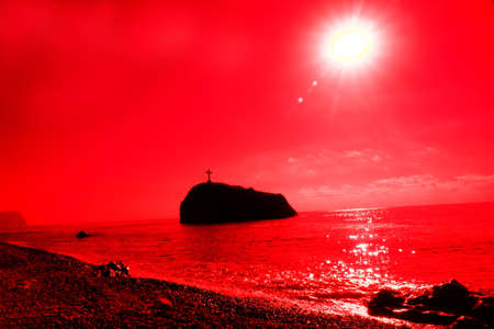 A rock in the sea with a cross on top. The Red Sea. Memory of the lost fishermen. Surrealistic art infrared photoの写真素材