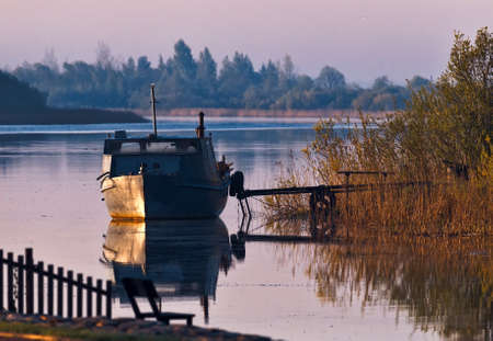 On the bank of the north quiet river. Spring, morning, calm. Fishing boat old, rural idyll