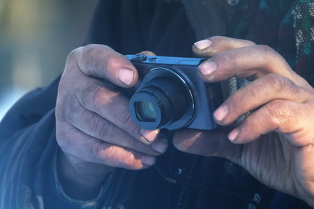 A tramp with a digital camera in his overworked hands. Snapshot detail