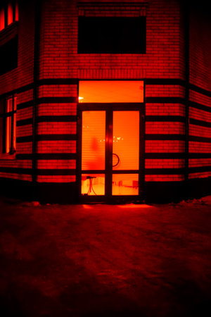 A glowing hall behind a glass door (behind blind) on a frosty winter night. Simultaneous feeling of warmth and cold. Surrealistic art infrared photoの写真素材