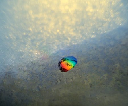 Early spring Zen rainbow stone on ice. Concept of onset of spring
