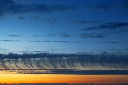 Unusual clouds in the post-sunset hour, like clouds of long straight locks (hair) descending to the...