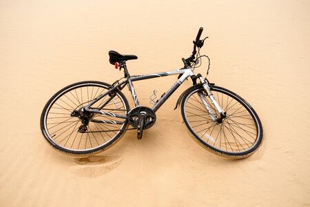 Bicycle left on sandy sea beach trail
