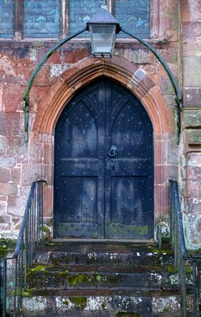 Close-up of traditional gothic medieval wooden entrance doorway with ancient brick arc and old fashioned lantern on top.の写真素材