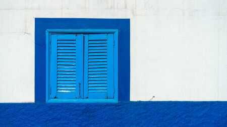 Mediterranean white washed house with blue wooden window shuttersの写真素材