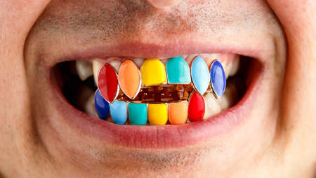 man wearing rainbow colored fake golden teeth Tooth Cap Jewelry party decoration.の写真素材
