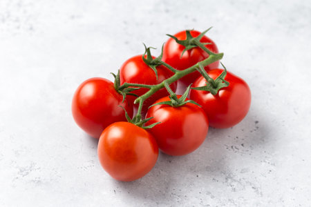 Bunch of fresh, red tomatoes on the vine on white backgroundの写真素材