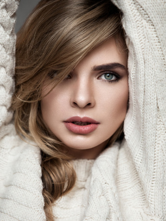 portrait of beautiful girl in a sweater on a gray backgroundの写真素材