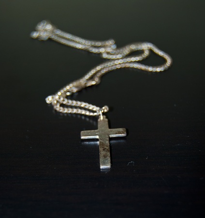 slightly decayed sterling silver crucifix on black surfaceの写真素材