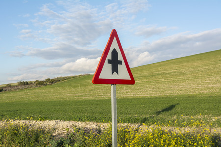 Road sign against green field, and blue sky with white cloudsの写真素材
