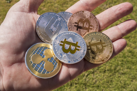 Cryptocurrency coins in a hand; Bitcoin, Ripple, Dash