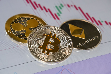 Cryptocurrency coins over trading graphic japanese candles; Bitcoin, Ethereum and Ripple coinsの写真素材