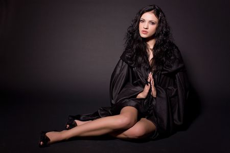 Praying nun sitting on the floor, isolated on black background の写真素材