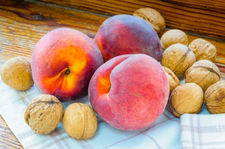 Three red peaches, and some walnuts close to the windowの写真素材