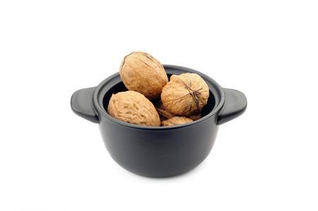 Walnuts in a black ceramic dish with handlesの写真素材