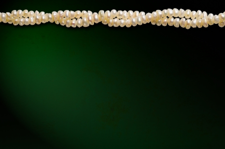 A line of natural pearls on a dark green background, with space for copy textの写真素材