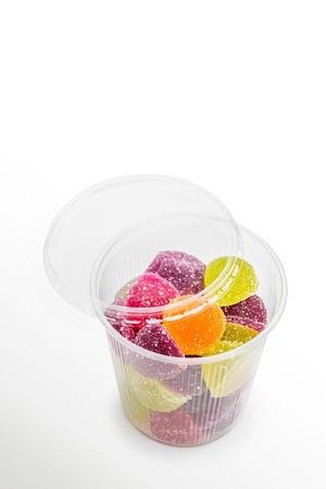 Colorful fruit jelly in open foam jar, on white の写真素材