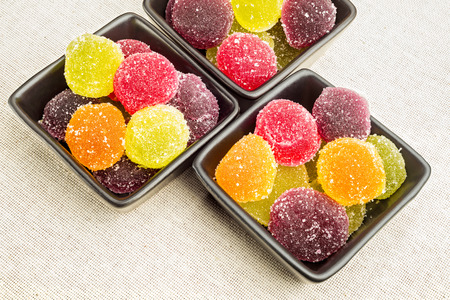 Colorful fruit jelly in little black ceramic cups, on a canapa fabric.の写真素材