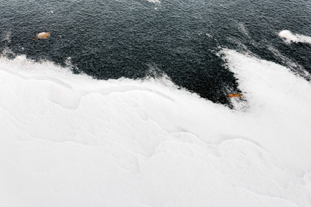 Closeup of frozen water on the Dnieper river in Kiev. The wind draws some abstract decorations on the snow.の写真素材