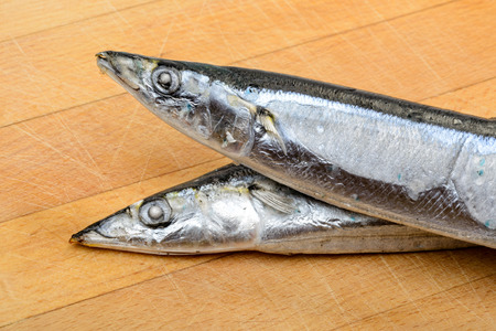 Detail of frozen Pacific Saury on  a wooden cutting boardの写真素材