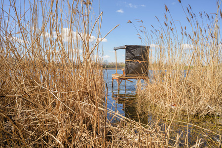 A wooden shelter over the lake is waiting for the fisherman under a blue and cloudy skyの写真素材