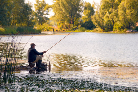 Kiev - Ukraine - July 16, 2014: An old fisherman is catching fishes in the Dnieper river in Kiev, in the Obolon districtのeditorial素材