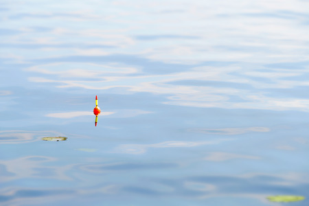 A yellow and orange fishing float in blue water