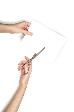A woman is cutting a sheet of white paper using  metallic scissors, isolated on white backgroundの写真素材