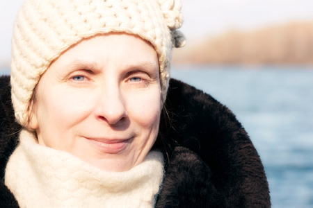 Portrait of an adult woman wearing a fur and a woolen cap in winter