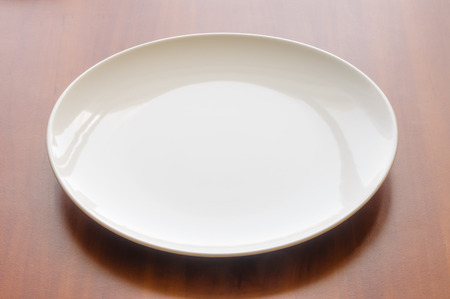An empty white modern plate on a wooden tableの写真素材