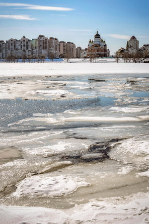 View of willow trees and poplars close to the frozen Dnieper River in Kiev during winter. High buildings and the Cathedral of Intercession of the Mother of God in the background.のeditorial素材