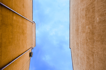 An abstract view of a building wall with blue sky and white cloudsの写真素材