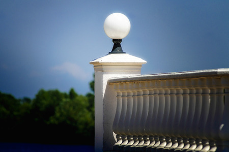 A white baluster with a lamp in front of the forest on the lake