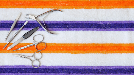 A set of tools for manicure and pedicure, composed of  scissors, clipper and nail file on a striped towelの写真素材