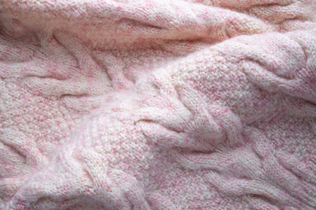 Soft folds of a warm pink knitted woolen pullover to be used as backgroundの写真素材