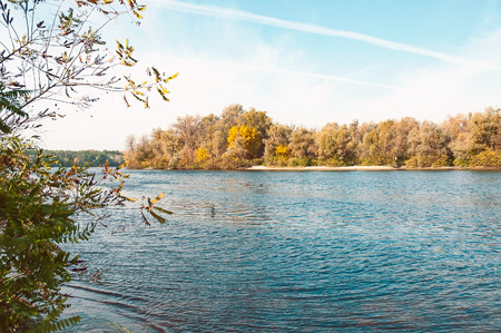 Sunny fall day close to the blue Dnieper river in Kiev, Ukraine, with autumn trees aroundの写真素材