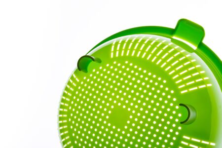 Close-up of a green plastic colander, a kitchen utensil to drain pasta, on a white background. Photo with copy space.の写真素材